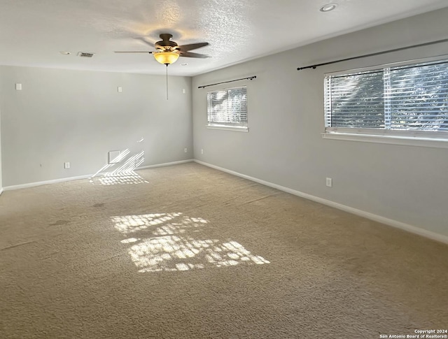 carpeted empty room with plenty of natural light, ceiling fan, and a textured ceiling