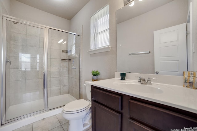 bathroom featuring tile patterned flooring, vanity, toilet, and walk in shower