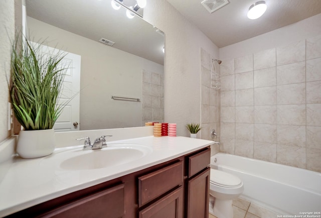 full bathroom featuring tile patterned flooring, vanity, toilet, and tiled shower / bath combo