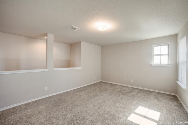 carpeted empty room with a textured ceiling