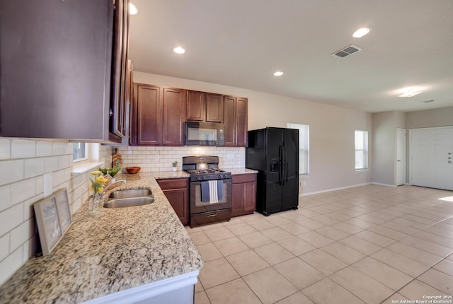 kitchen with light stone countertops, decorative backsplash, sink, black appliances, and light tile patterned floors