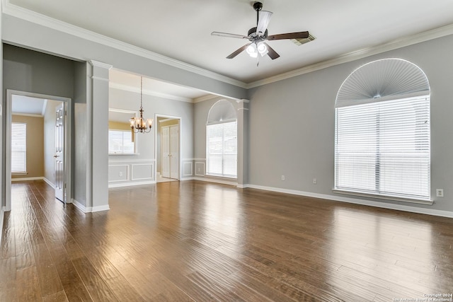 empty room with ceiling fan with notable chandelier, dark wood-type flooring, ornate columns, and crown molding