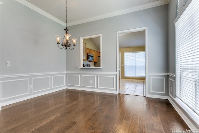 unfurnished room featuring dark hardwood / wood-style flooring, lofted ceiling, crown molding, and an inviting chandelier