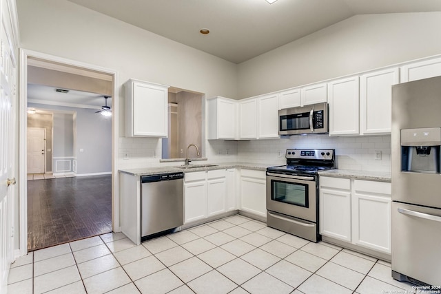 kitchen with light stone countertops, stainless steel appliances, sink, light tile patterned floors, and white cabinetry