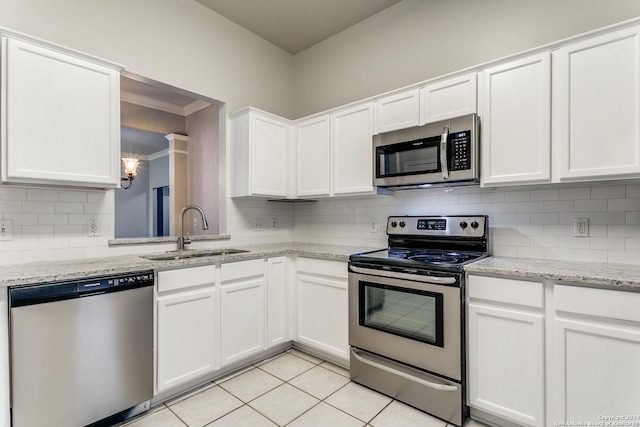 kitchen with sink, light stone countertops, light tile patterned floors, white cabinetry, and stainless steel appliances