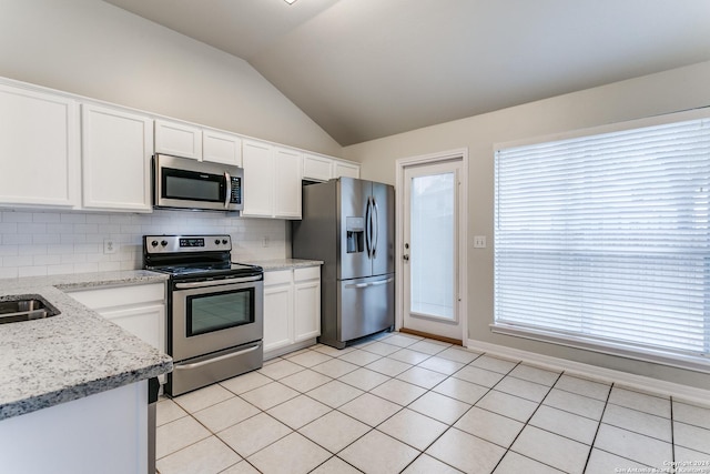 kitchen featuring vaulted ceiling, decorative backsplash, light stone counters, white cabinetry, and stainless steel appliances