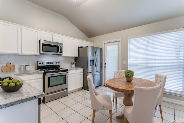 kitchen with decorative backsplash, appliances with stainless steel finishes, white cabinets, lofted ceiling, and light tile patterned flooring