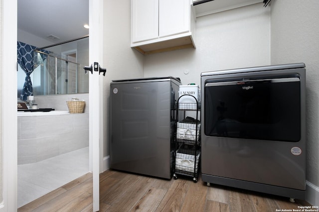 washroom featuring light hardwood / wood-style floors, cabinets, and independent washer and dryer