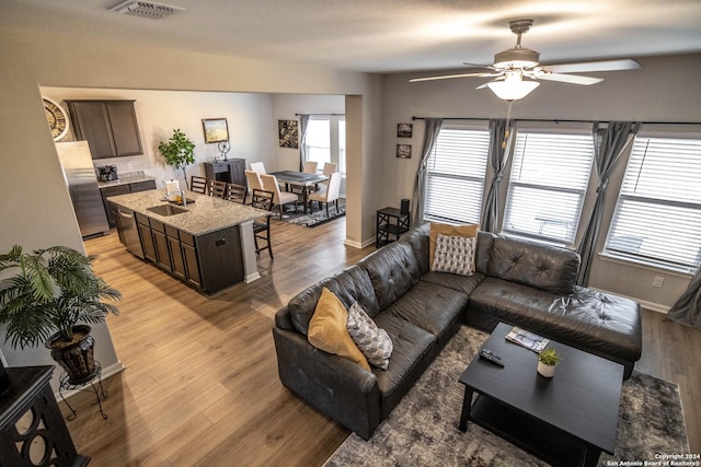 living room with ceiling fan, sink, and light hardwood / wood-style floors