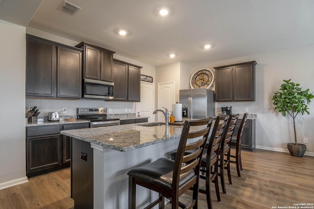 kitchen featuring appliances with stainless steel finishes, light hardwood / wood-style flooring, dark brown cabinets, and sink