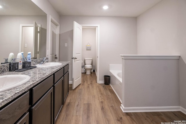 bathroom with hardwood / wood-style floors, vanity, toilet, and a bath