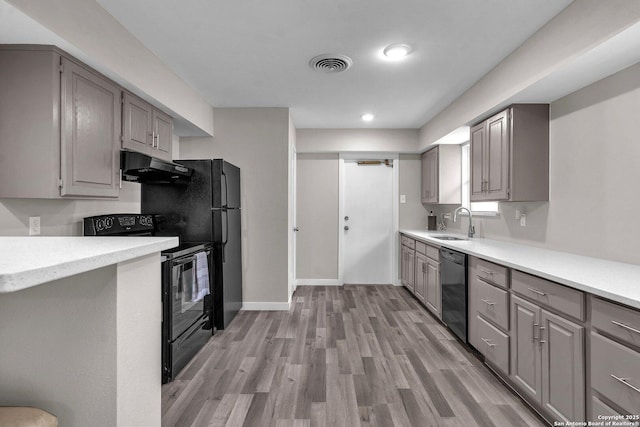 kitchen with sink, gray cabinets, light hardwood / wood-style floors, and black appliances