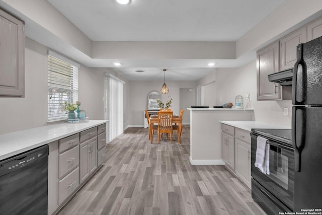 kitchen featuring light wood-type flooring, ventilation hood, black appliances, gray cabinets, and hanging light fixtures