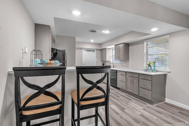 kitchen featuring black appliances, gray cabinets, light hardwood / wood-style floors, and sink