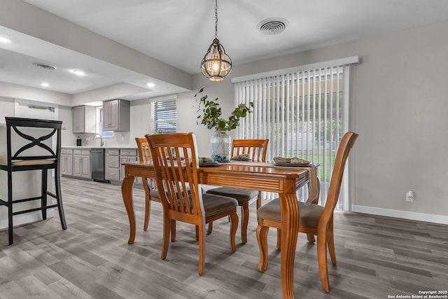 dining area featuring sink, plenty of natural light, an inviting chandelier, and light wood-type flooring