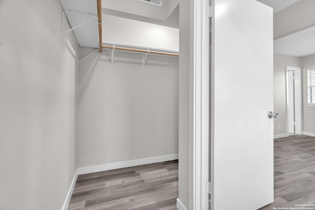 walk in closet with light hardwood / wood-style floors