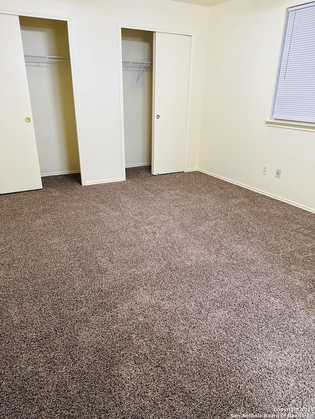 unfurnished bedroom featuring carpet floors and two closets