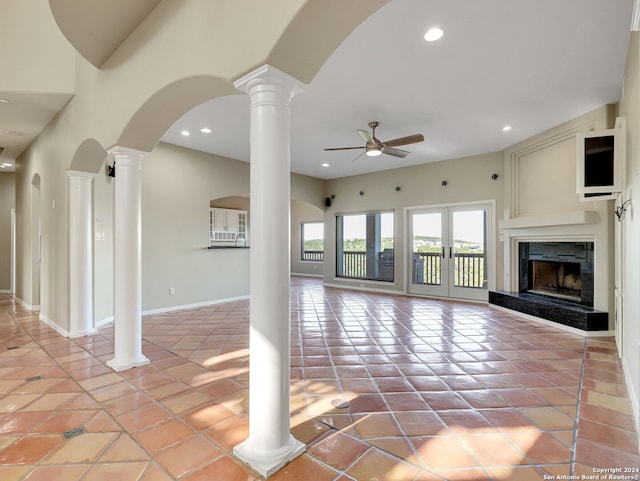 unfurnished living room featuring ceiling fan, french doors, a premium fireplace, a towering ceiling, and light tile patterned floors