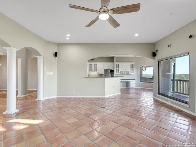 unfurnished living room with ornate columns, ceiling fan, and light tile patterned floors