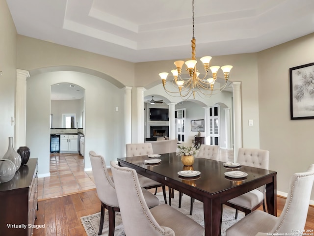 dining room featuring a notable chandelier, a raised ceiling, wood-type flooring, and sink