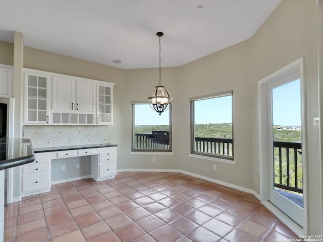 kitchen featuring backsplash, white cabinets, built in desk, decorative light fixtures, and light tile patterned flooring