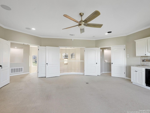 unfurnished living room featuring ceiling fan, light colored carpet, ornamental molding, and sink