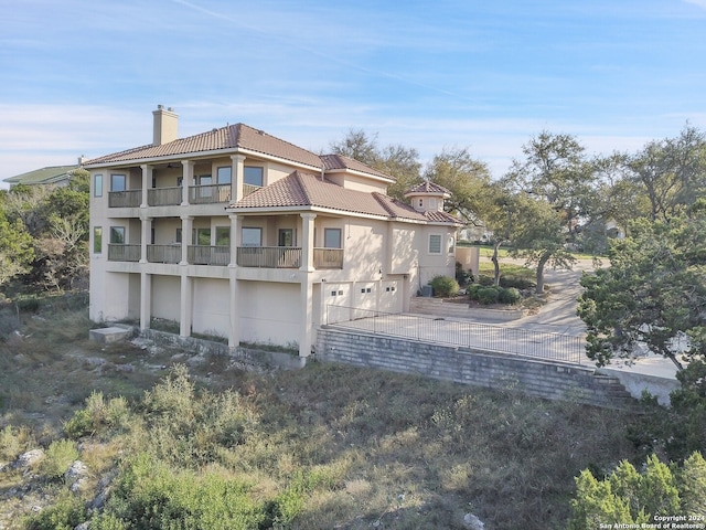 back of property featuring a balcony and a garage