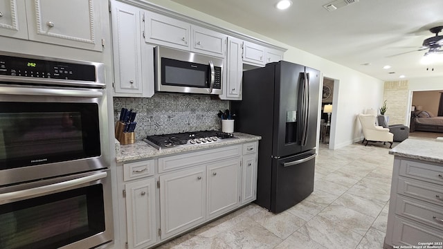 kitchen with decorative backsplash, appliances with stainless steel finishes, white cabinetry, and ceiling fan