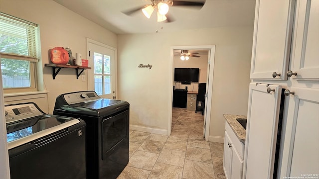 clothes washing area featuring ceiling fan, washer and clothes dryer, and cabinets