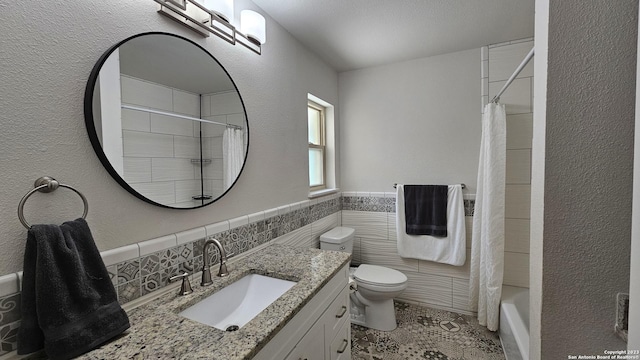 full bathroom with vanity, toilet, shower / bath combo with shower curtain, and tile walls