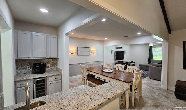 kitchen with decorative backsplash, light stone counters, and beverage cooler