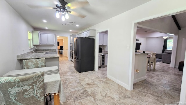 kitchen featuring ceiling fan, sink, beverage cooler, kitchen peninsula, and black refrigerator