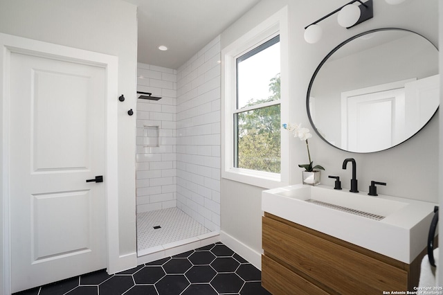 bathroom with tile patterned flooring, vanity, a tile shower, and a wealth of natural light