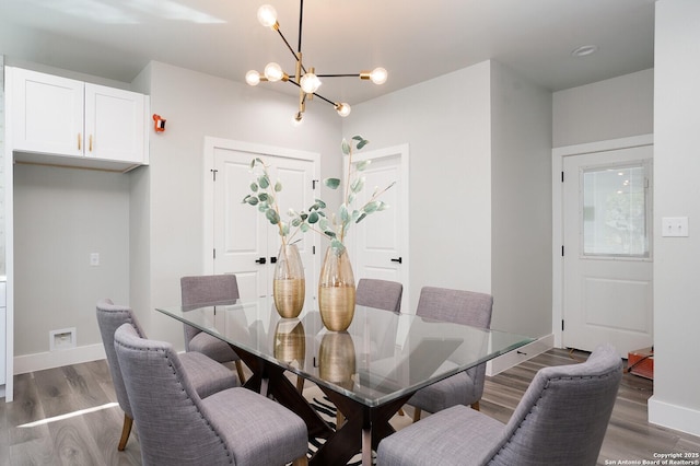 dining area featuring hardwood / wood-style flooring and an inviting chandelier