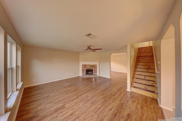 unfurnished living room featuring a stone fireplace, ceiling fan, and light wood-type flooring