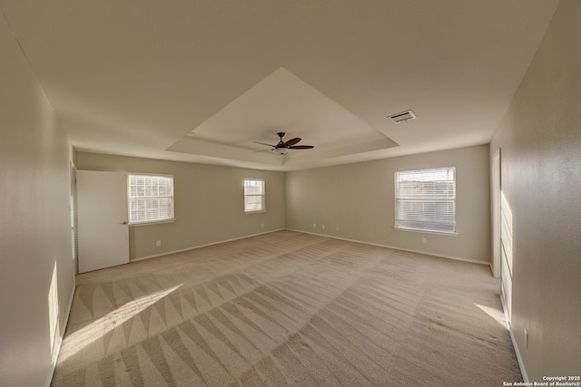 carpeted spare room with a tray ceiling and ceiling fan