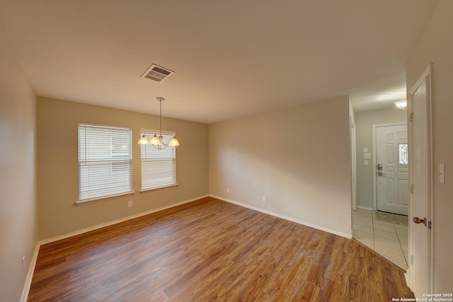 unfurnished room with a chandelier and hardwood / wood-style flooring