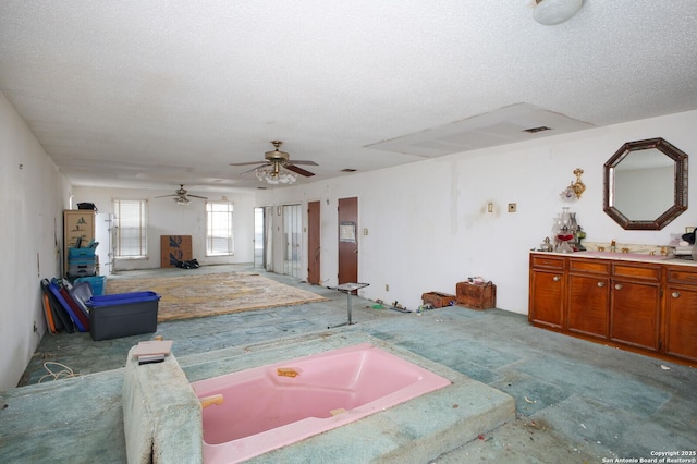 living room featuring ceiling fan, sink, and a textured ceiling