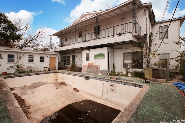 back of property featuring a balcony and an empty pool