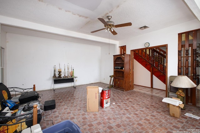 living room with ceiling fan and a textured ceiling