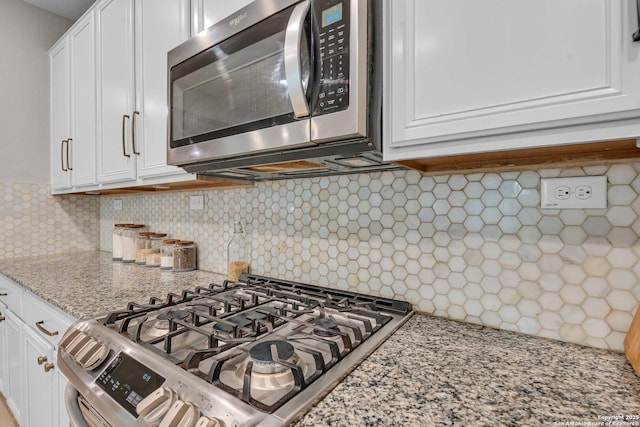 kitchen with decorative backsplash, range, white cabinets, and light stone counters