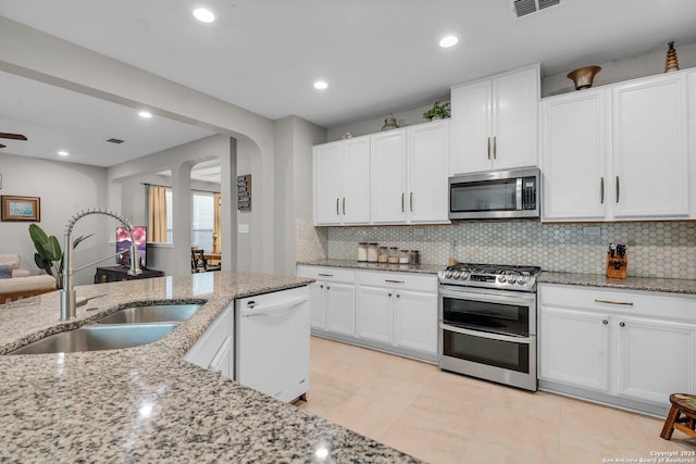 kitchen featuring backsplash, sink, light stone counters, white cabinetry, and stainless steel appliances