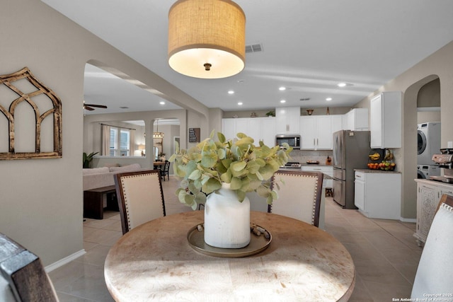 dining area featuring stacked washer / dryer, ceiling fan, and light tile patterned floors