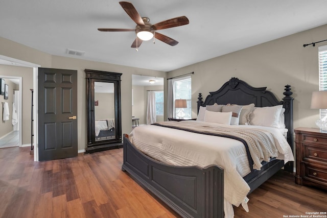 bedroom with ceiling fan, dark hardwood / wood-style flooring, ensuite bath, and multiple windows