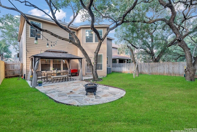 rear view of property featuring a gazebo, a yard, a patio, and a fire pit