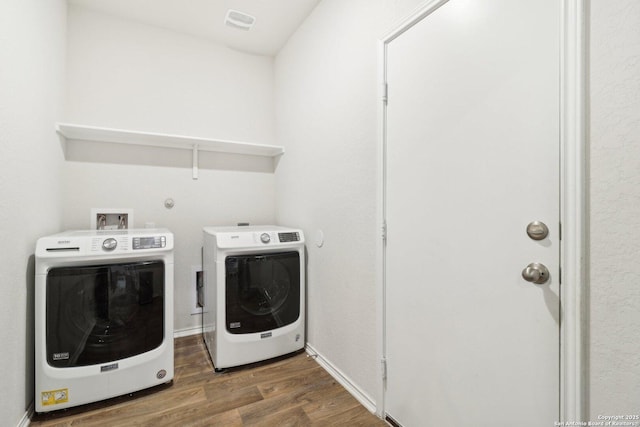 clothes washing area featuring washing machine and clothes dryer, heating unit, and dark hardwood / wood-style flooring