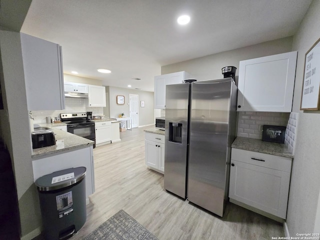 kitchen with white cabinetry, black range with electric cooktop, light stone counters, light hardwood / wood-style flooring, and stainless steel fridge