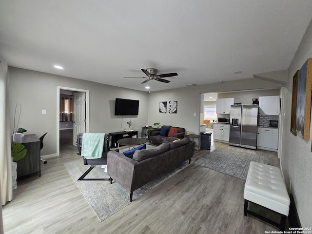 living room with light hardwood / wood-style flooring and ceiling fan