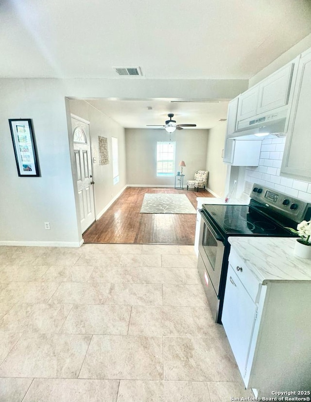 kitchen featuring stainless steel range with electric cooktop, ceiling fan, tasteful backsplash, light stone counters, and white cabinetry