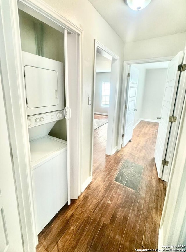 clothes washing area featuring stacked washer and dryer and dark hardwood / wood-style floors